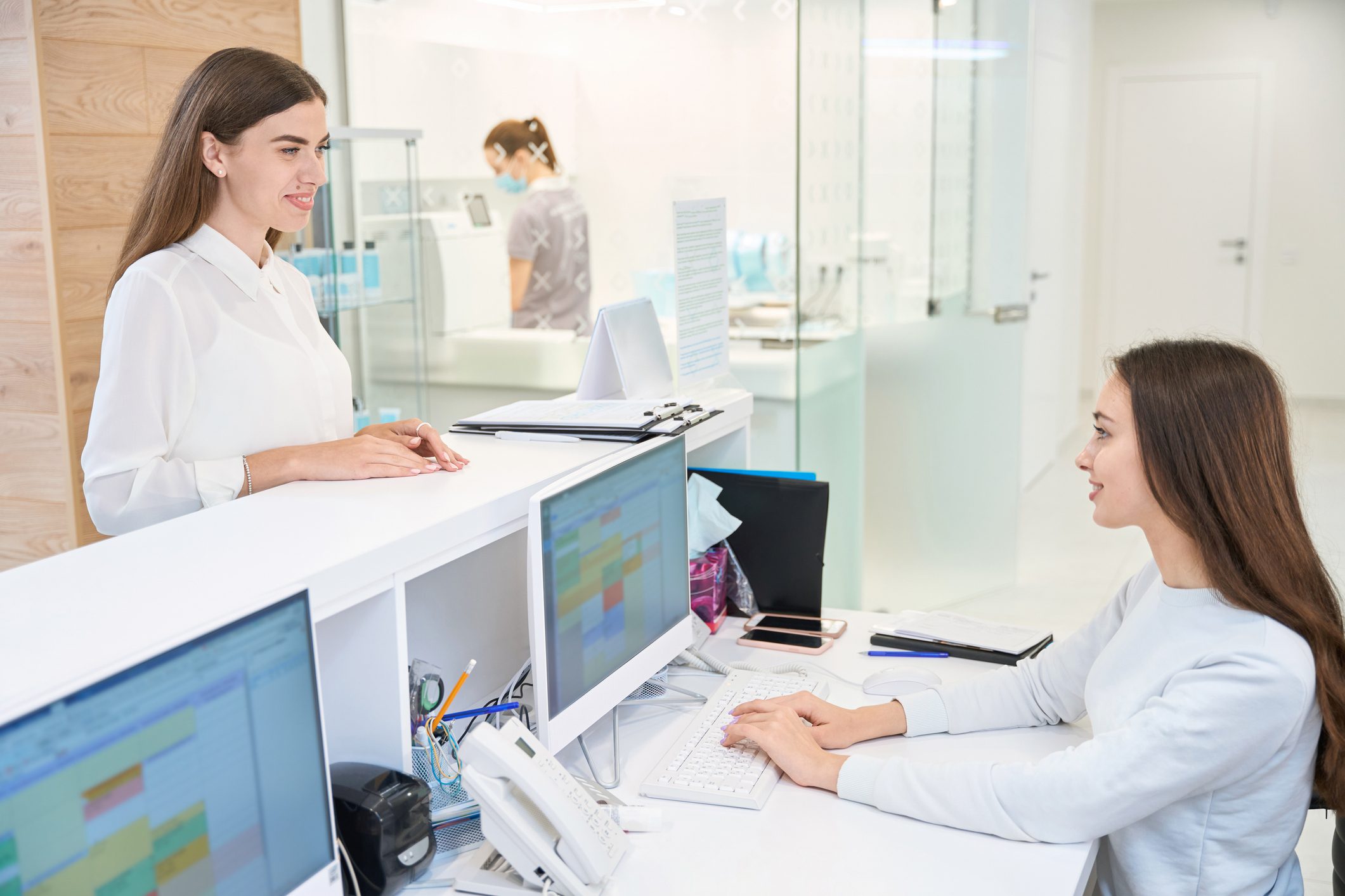 Receptionist assisting a woman at the desk.