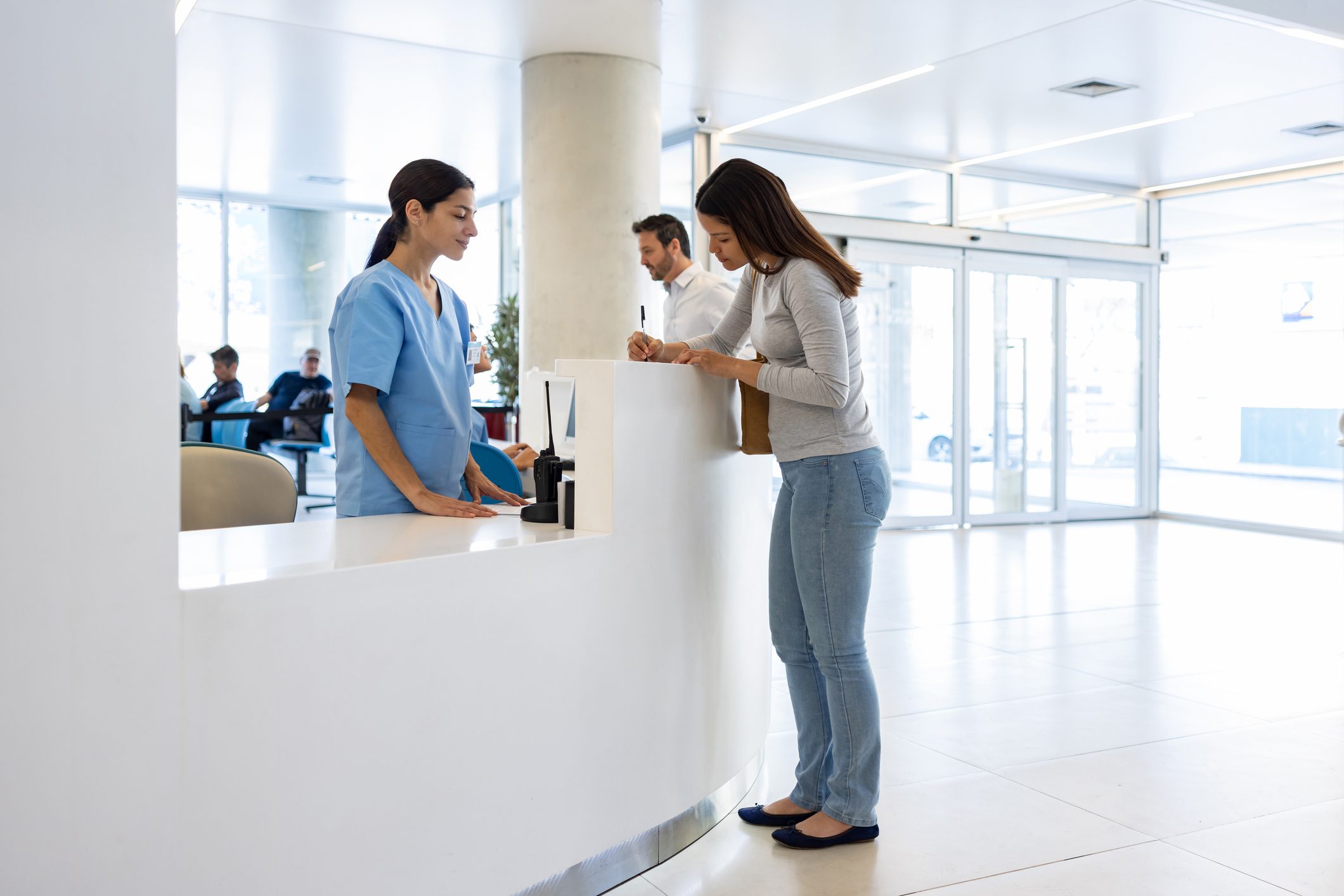 Woman checking in at hospital reception desk.