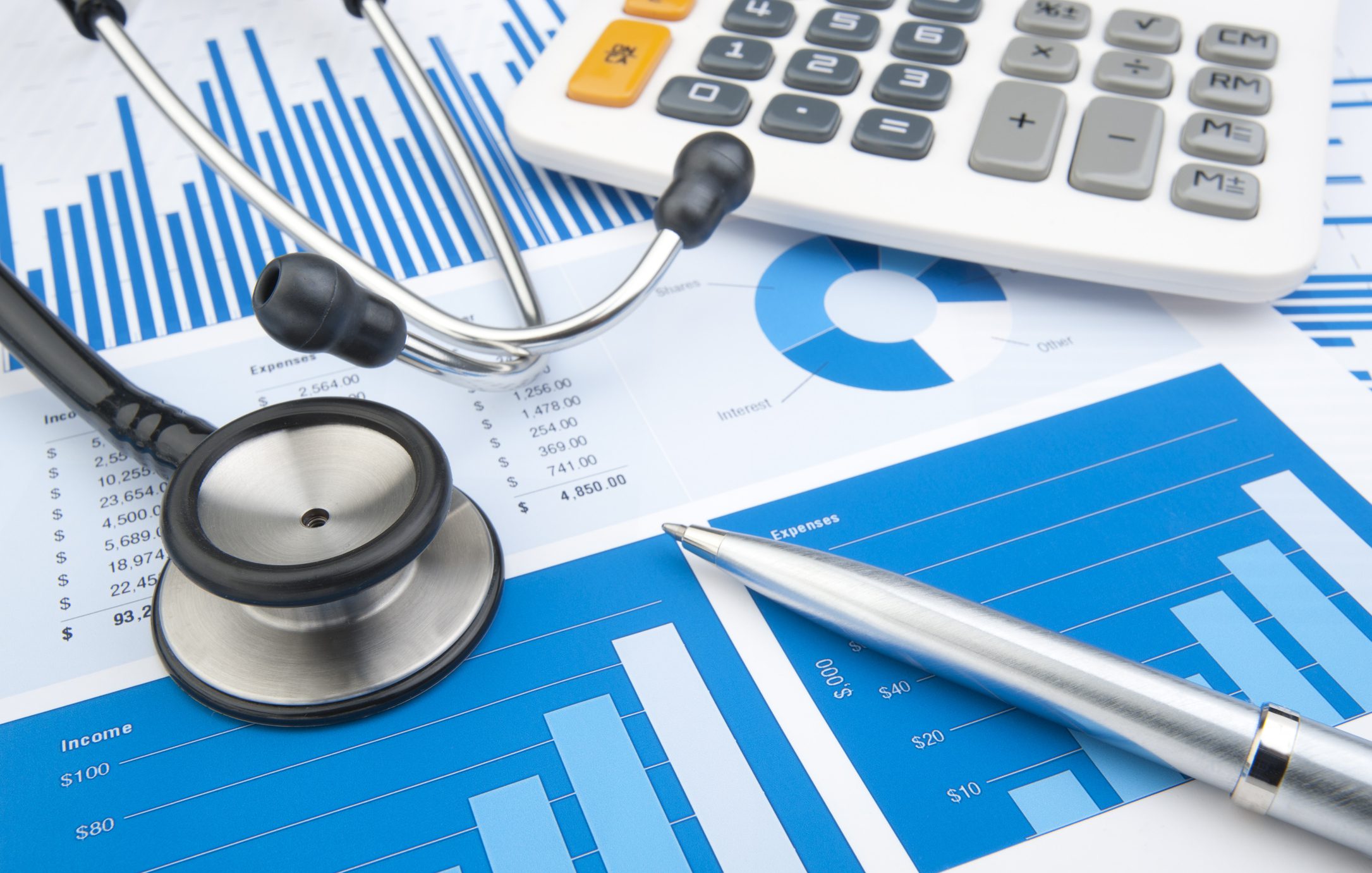 Stethoscope and calculator on financial charts.