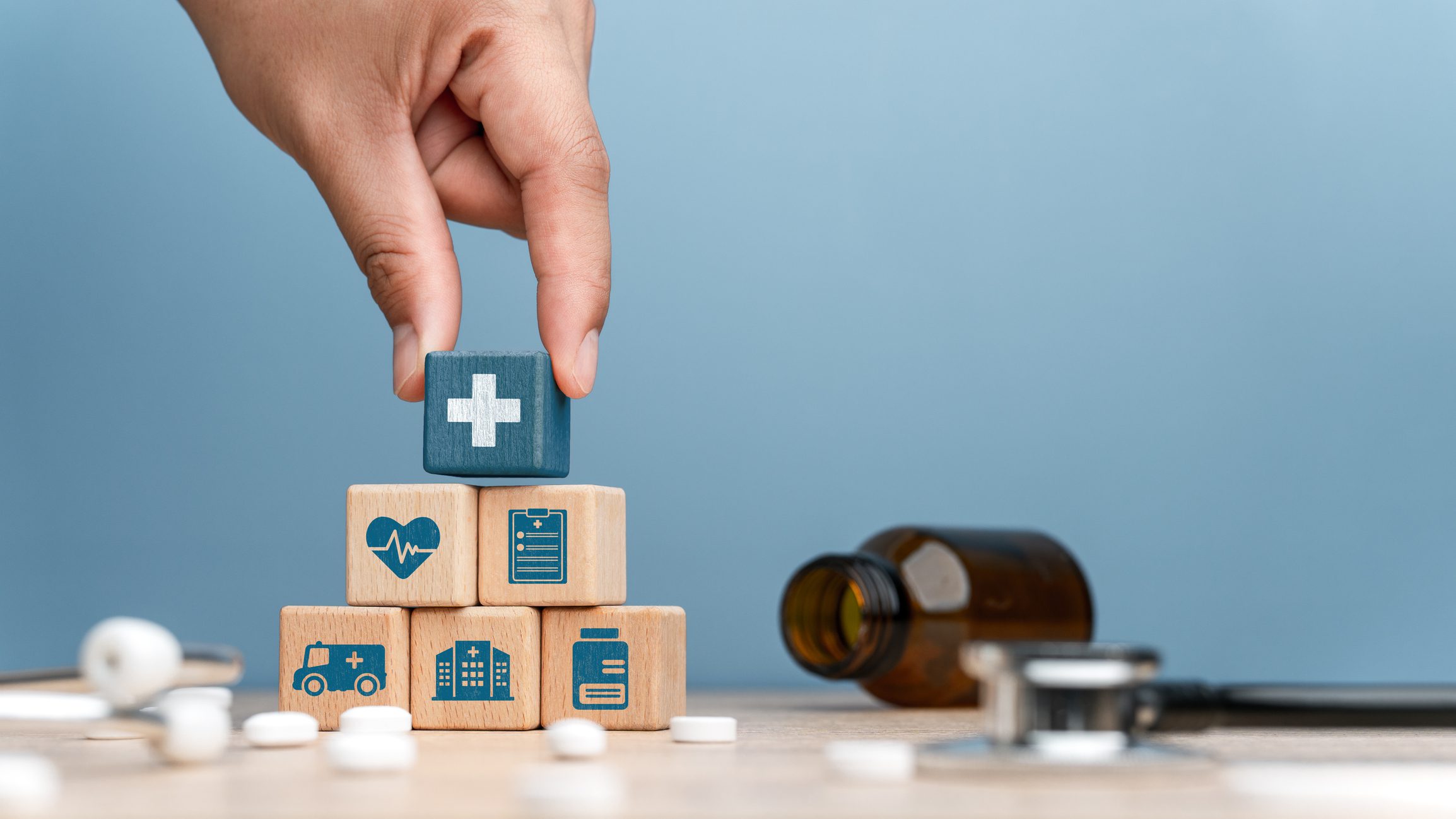 Hand stacking healthcare-related wooden blocks.